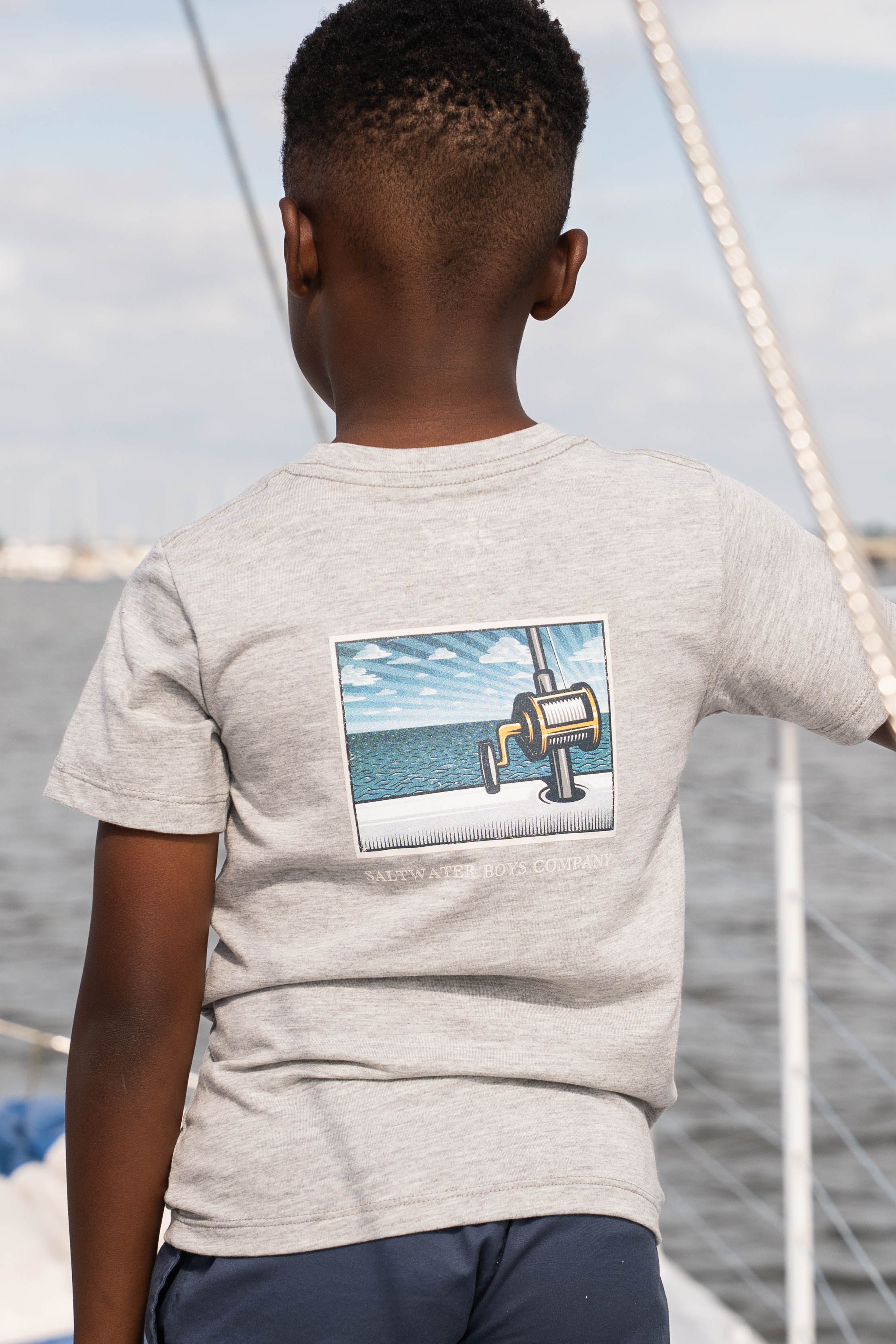 Child on a sailboat wearing a t-shirt with a graphic design