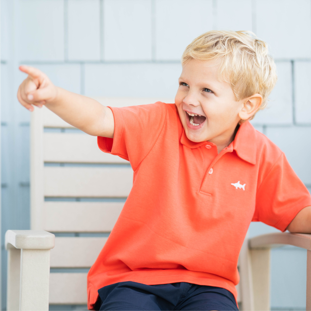 boy holding a football in a polo shirt