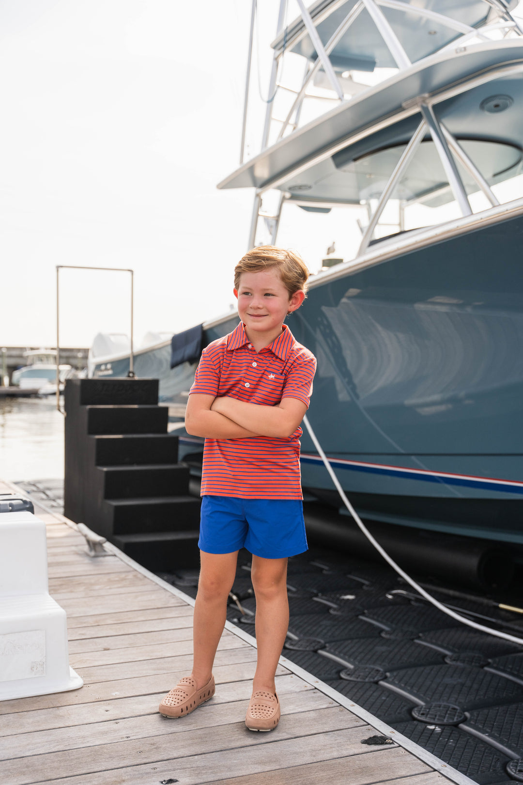 Young boy standing on a dock with a boat in the background